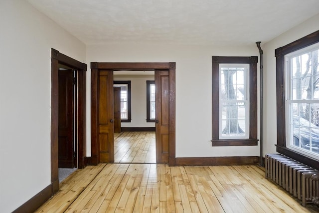 interior space featuring radiator heating unit and light hardwood / wood-style flooring