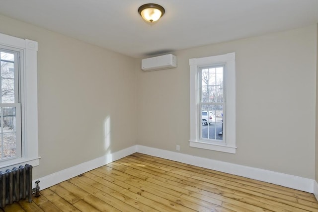 spare room featuring radiator, an AC wall unit, and light hardwood / wood-style flooring