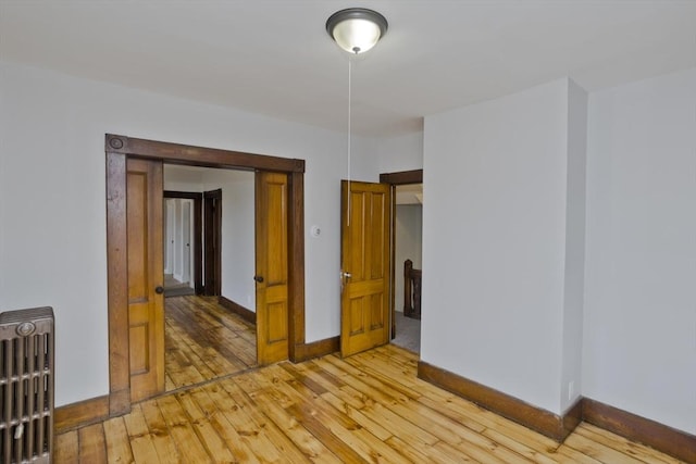 empty room featuring light wood-type flooring and radiator heating unit