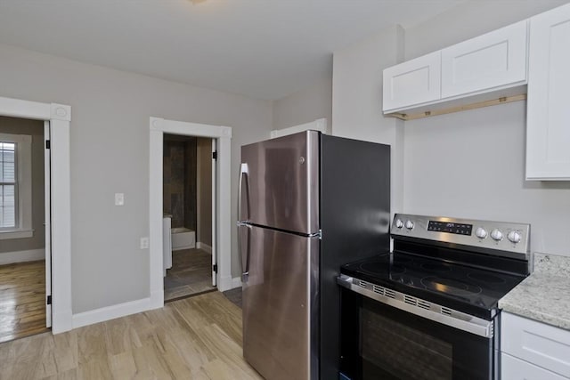 kitchen featuring light stone counters, white cabinetry, appliances with stainless steel finishes, and light hardwood / wood-style flooring