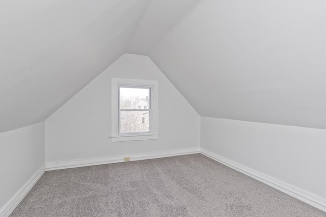 additional living space with vaulted ceiling and carpet flooring