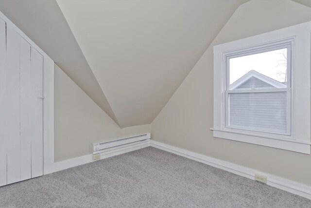 additional living space with light colored carpet, vaulted ceiling, and a baseboard radiator