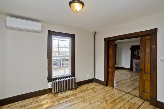 unfurnished room featuring a wall mounted AC, radiator heating unit, and light hardwood / wood-style floors