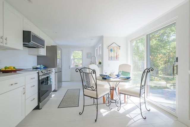 kitchen featuring light tile patterned flooring, white cabinetry, stainless steel appliances, and plenty of natural light