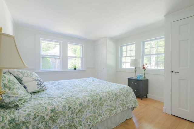 bedroom featuring ornamental molding and light wood-type flooring