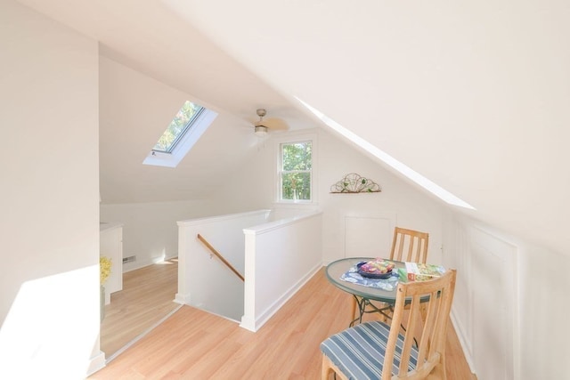 additional living space featuring light hardwood / wood-style flooring, lofted ceiling with skylight, and ceiling fan