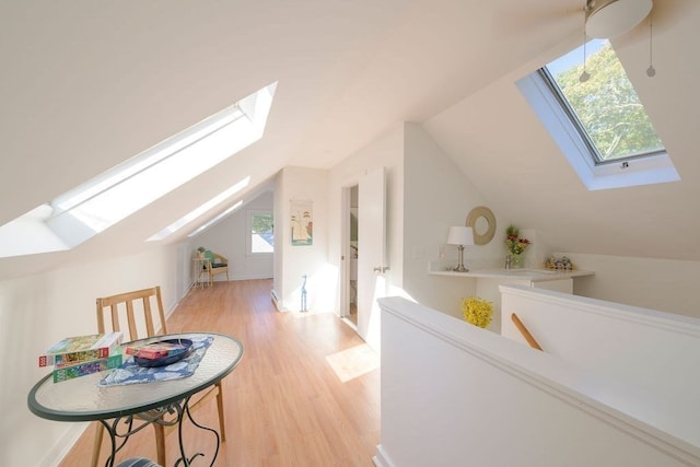 bonus room featuring vaulted ceiling with skylight and light wood-type flooring