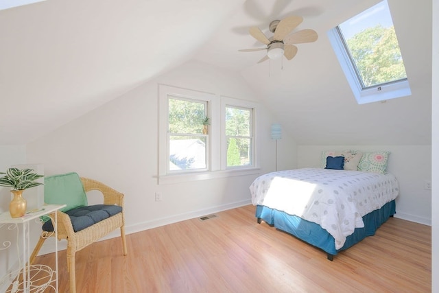 bedroom with lofted ceiling with skylight, hardwood / wood-style flooring, and ceiling fan