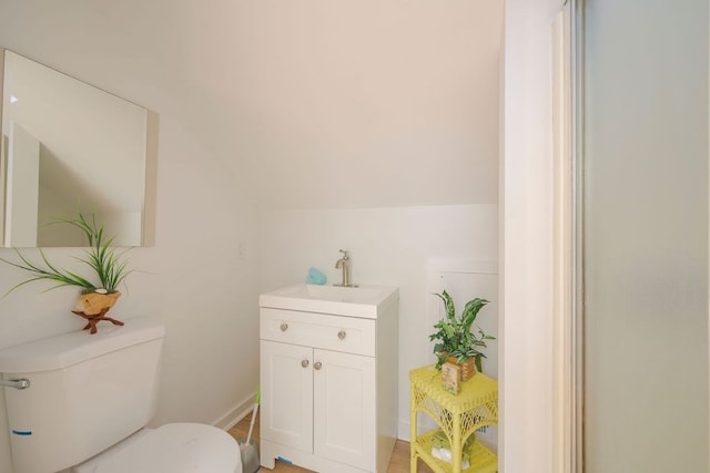 bathroom featuring toilet, lofted ceiling, vanity, and wood-type flooring