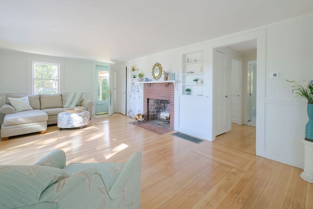 living room featuring light hardwood / wood-style floors, built in features, and a fireplace