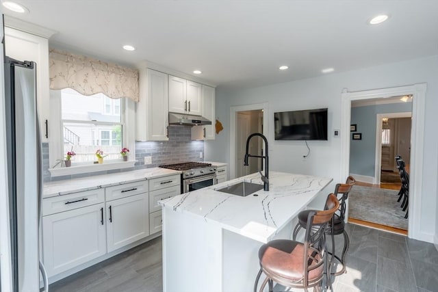 37 Chestnut St, Stoneham, MA 02180 - kitchen with stainless steel appliances, a sink, under cabinet range hood, white cabinets, and decorative backsplash