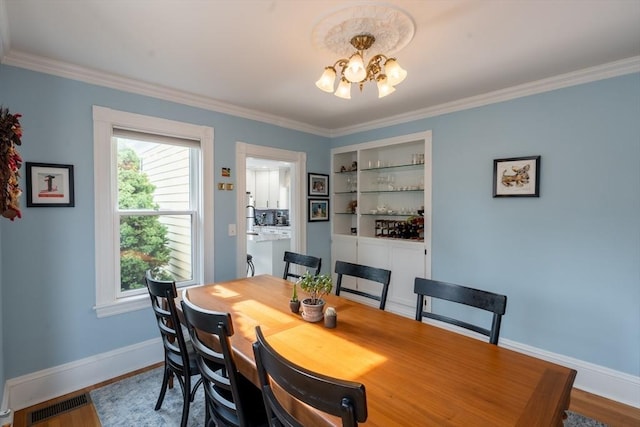 37 Chestnut St, Stoneham, MA 02180 - dining area featuring a chandelier, baseboards, crown molding, healthy amount of natural light, and wood finished floors