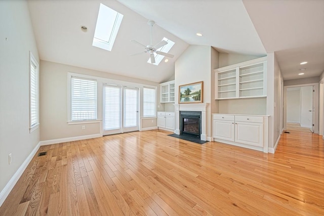 unfurnished living room with a skylight, a fireplace with flush hearth, baseboards, high vaulted ceiling, and light wood-style flooring