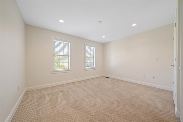 empty room featuring baseboards, recessed lighting, and light colored carpet