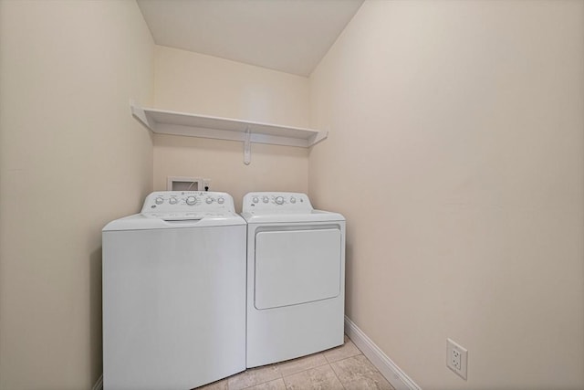 washroom with light tile patterned floors, baseboards, laundry area, and washer and clothes dryer