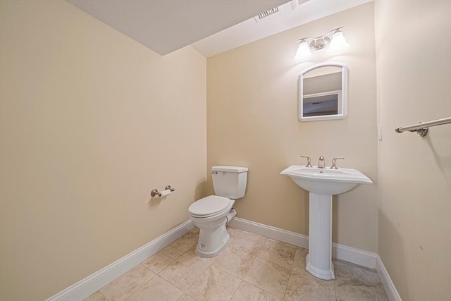 half bath featuring baseboards, a sink, and toilet