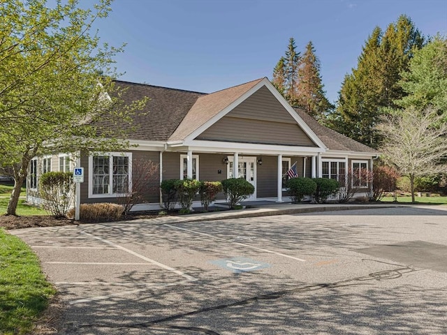 view of front facade featuring covered porch, uncovered parking, and a shingled roof