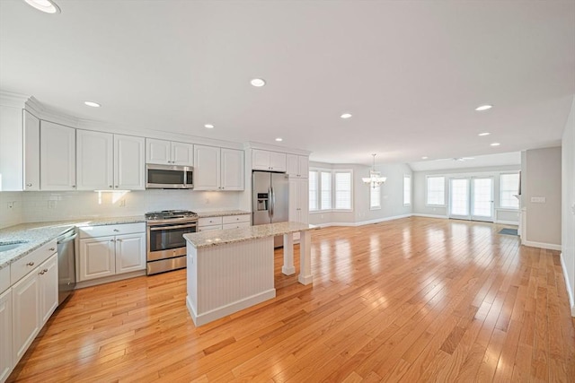 kitchen with baseboards, white cabinetry, a center island, and stainless steel appliances