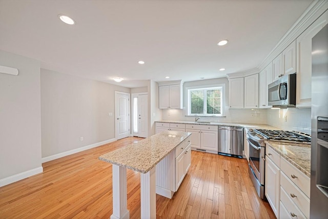 kitchen with baseboards, white cabinetry, tasteful backsplash, a sink, and stainless steel appliances