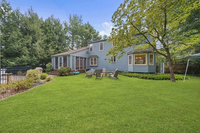 rear view of property with a lawn, fence, and a sunroom