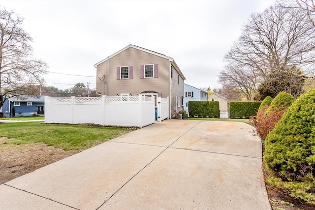 view of home's exterior featuring driveway, a yard, and fence
