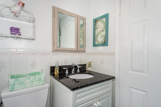 bathroom with toilet, a wainscoted wall, tile walls, and vanity