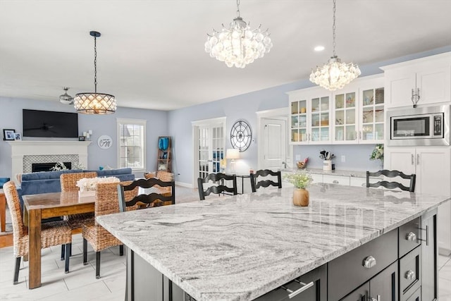 15 Day Lily Ln, Walpole, MA 02081 - kitchen featuring stainless steel microwave, a chandelier, open floor plan, decorative light fixtures, and white cabinetry