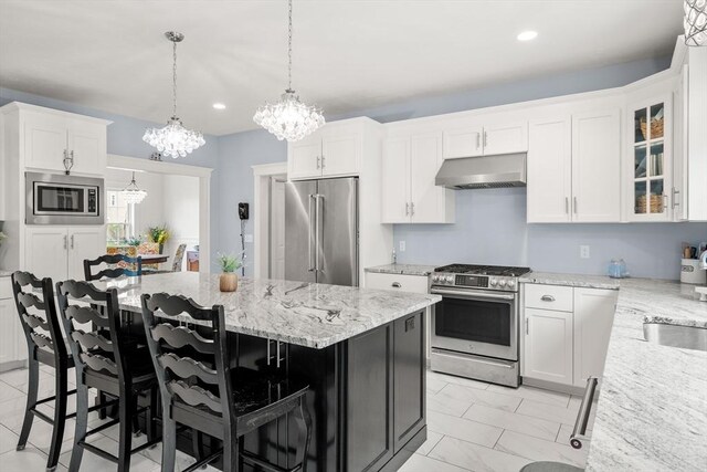 15 Day Lily Ln, Walpole, MA 02081 - kitchen with stainless steel appliances, under cabinet range hood, a chandelier, light stone countertops, and white cabinets