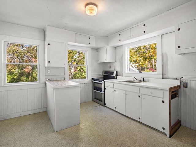 8 Rock Harbor Rd, Orleans, MA 02653 - kitchen with range with two ovens, light countertops, a sink, white cabinetry, and a wainscoted wall