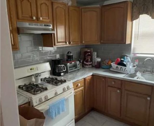 kitchen with sink, white gas stove, and decorative backsplash