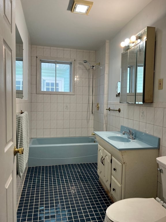 full bathroom with vanity, tile walls, toilet, and tiled shower / bath combo