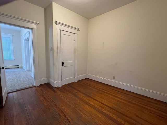 unfurnished room with a baseboard radiator and dark hardwood / wood-style flooring