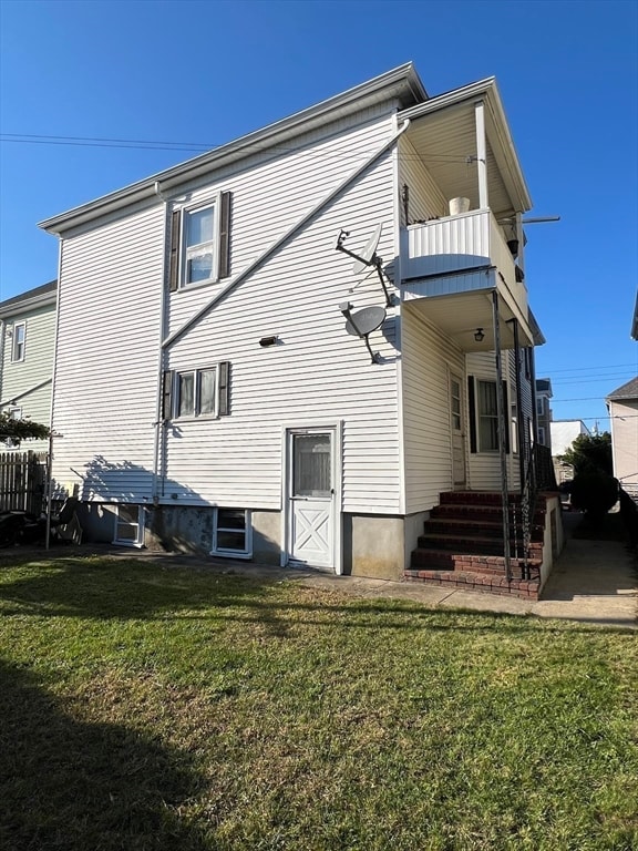 rear view of house with a balcony and a lawn