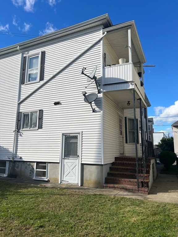 view of home's exterior with a balcony and a yard