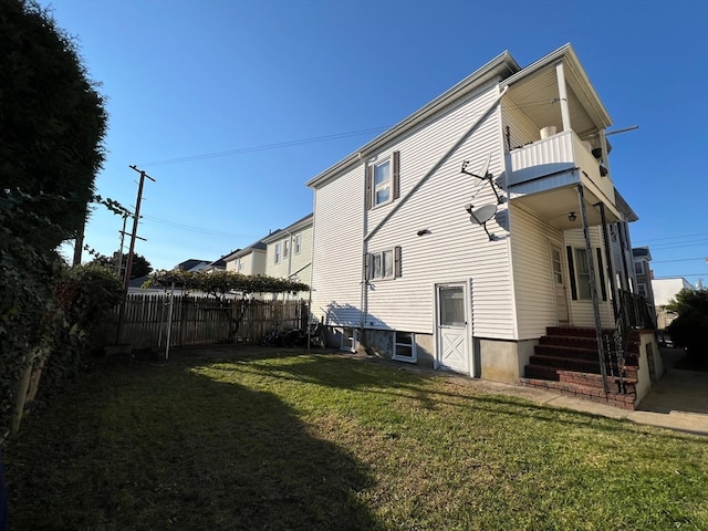 back of property featuring a balcony and a lawn