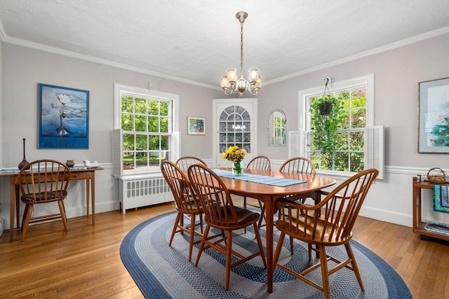 dining area with light wood finished floors, crown molding, and a chandelier