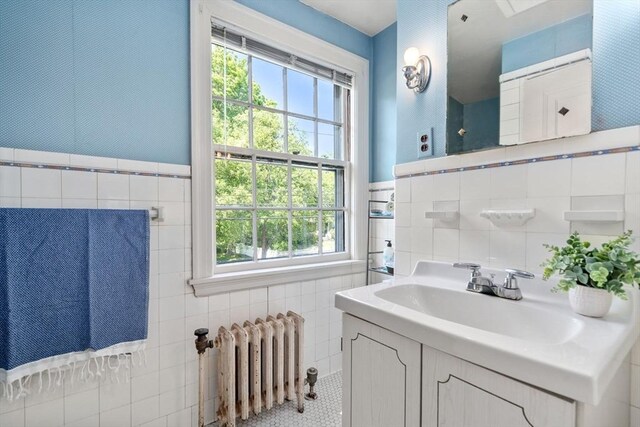 bathroom featuring radiator, tile walls, and vanity