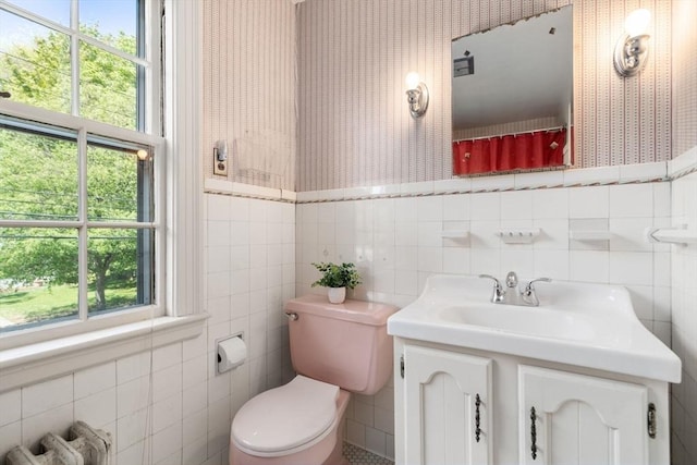 bathroom with toilet, tile walls, vanity, and wallpapered walls