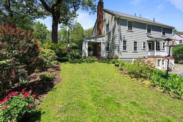 back of property with a chimney and a yard