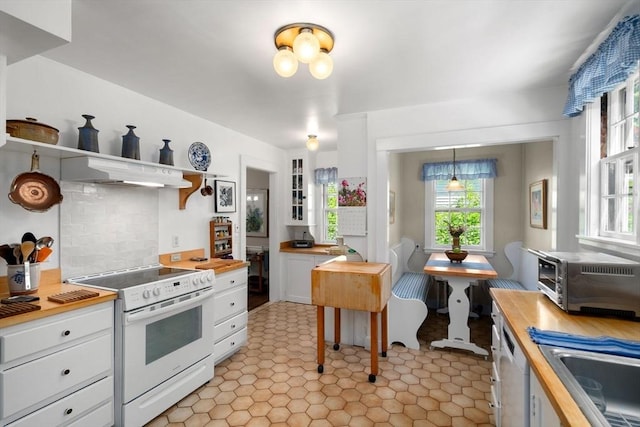 kitchen with white appliances, under cabinet range hood, butcher block counters, white cabinets, and a sink