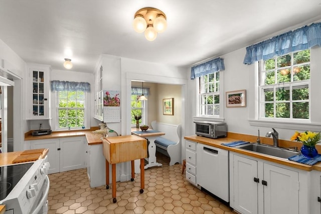 kitchen featuring butcher block counters, dishwasher, white cabinetry, glass insert cabinets, and range with electric cooktop
