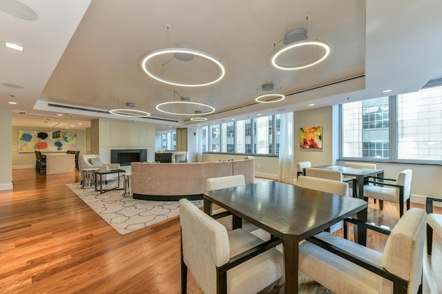 dining space featuring a raised ceiling, light wood-type flooring, and baseboards