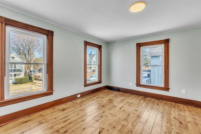 spare room featuring light wood-type flooring and crown molding