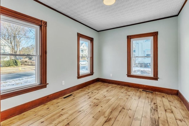 spare room with light wood-type flooring and crown molding