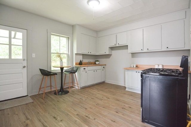 318 Charles St, Fitchburg, MA 01420 - kitchen with gas stove, light wood-style floors, white cabinets, and baseboards