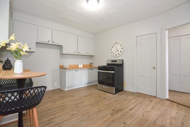 318 Charles St, Fitchburg, MA 01420 - kitchen with stainless steel gas range oven, white cabinetry, light wood-style flooring, baseboards, and light countertops