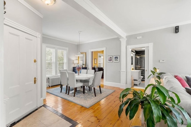 dining area with radiator heating unit, light hardwood / wood-style floors, decorative columns, and ornamental molding