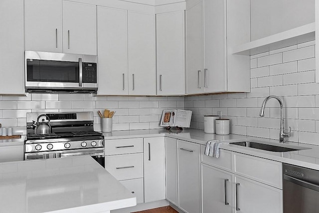 kitchen with white cabinets, backsplash, sink, and stainless steel appliances