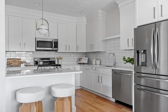 kitchen featuring white cabinets, appliances with stainless steel finishes, sink, hanging light fixtures, and a breakfast bar area