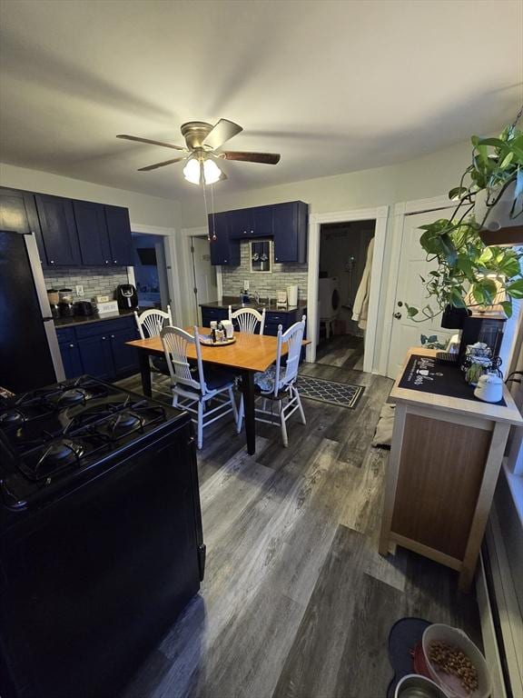 kitchen featuring dark wood-type flooring, stainless steel fridge, blue cabinetry, gas stove, and decorative backsplash